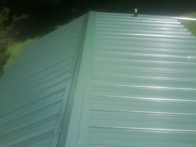 New green metal panels meeting at the ridge of a roof — Flat Roof Repair work by our crew in Fort Sill