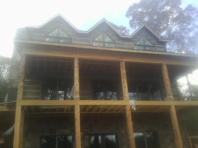 Dormers and porch framing on a large log home under construction — Roof Coating work by our crew in Fort Sill