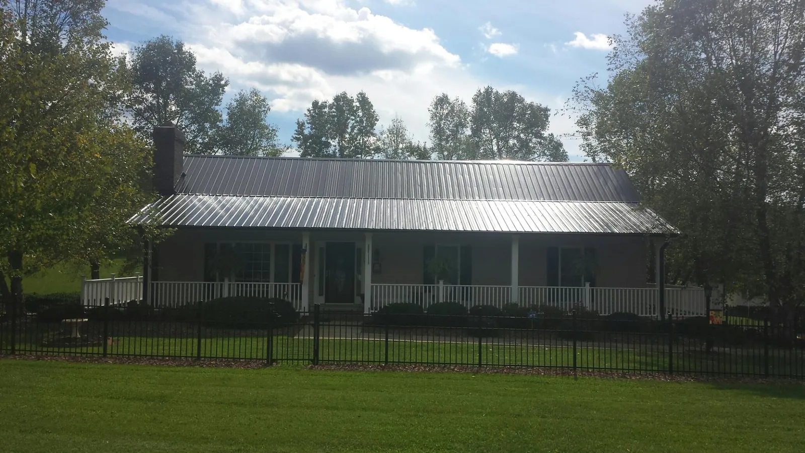 Gray metal roof on a brick ranch with a full width front porch — Gutter Guard Installation work by our crew in Fort Sill