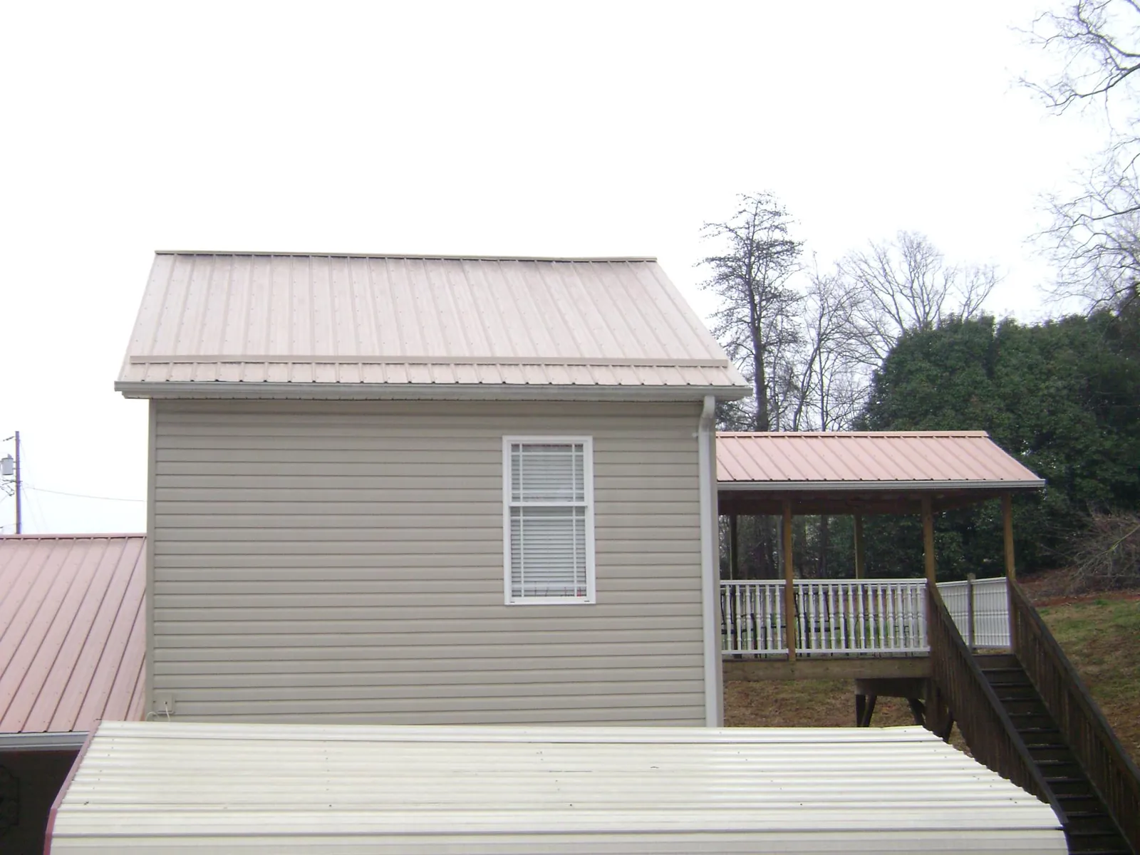 Tan metal roofs on a two story addition and attached porch, from a Roof Replacement job in Fort Sill