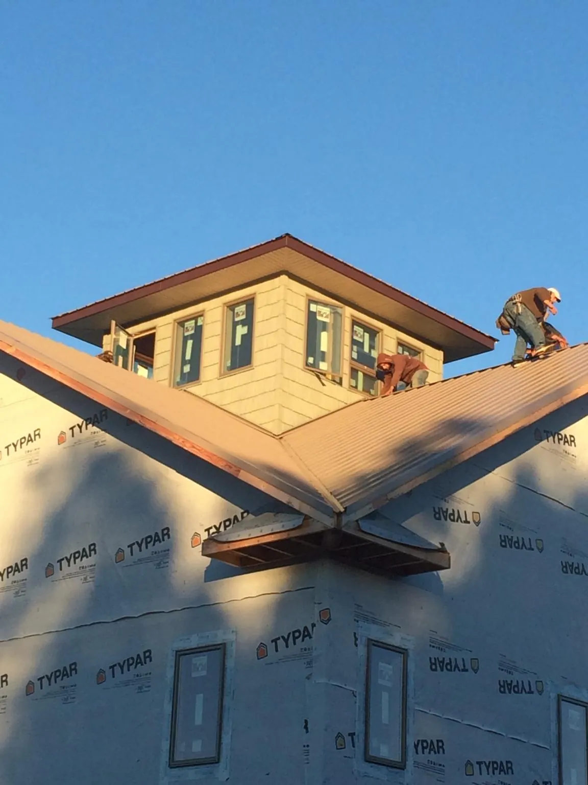 Roofers working around a rooftop cupola on a new metal roof at sunset — Roof Waterproofing in Fort Sill by Roofing Brothers